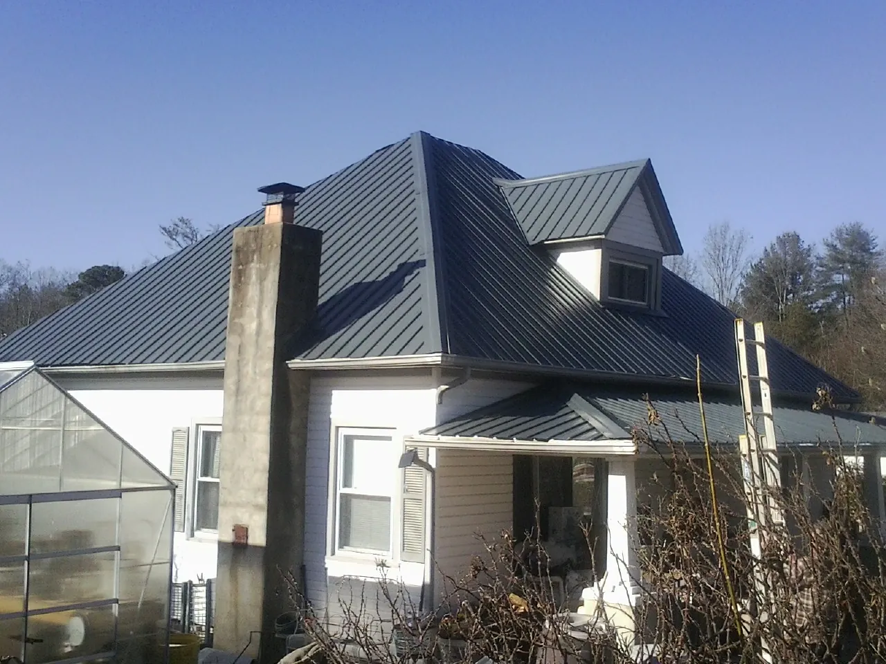 Dark blue standing seam metal roof on a white farmhouse with dormer — Slate & Tile Roof Repair by Roofing Brothers in Darien